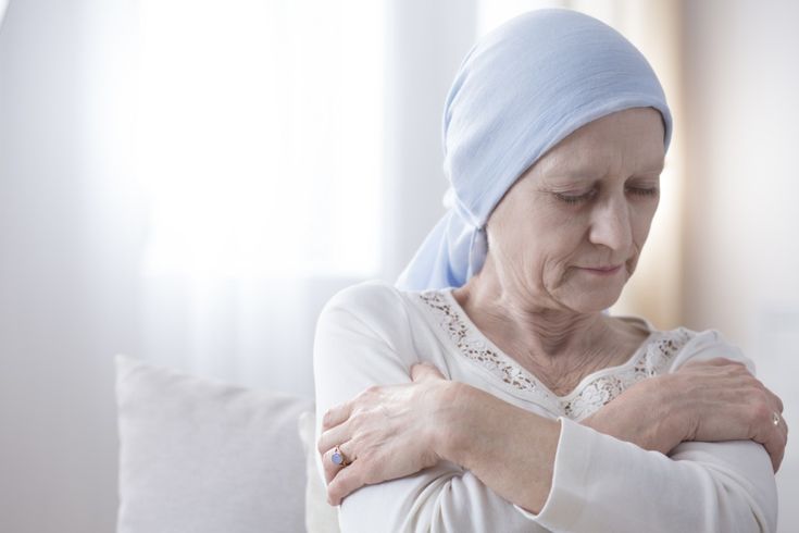 A woman sitting quietly with a neutral expression, reflecting awareness and attentiveness to subtle changes in her body that could indicate early signs of cancer.