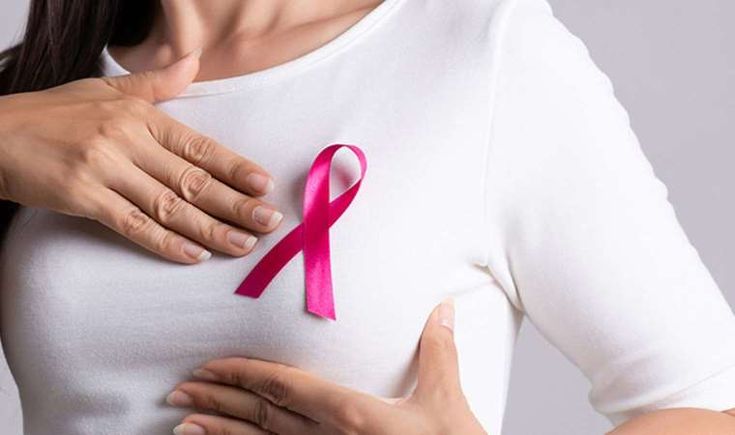 Woman performing breast self-examination in front of a mirror, checking for visual changes.